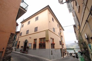 A hotel with a stone facade, multiple windows, and a view of a body of water. - Castel Gandolfo (Castel Gandolfo)