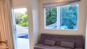 A modern living room with a sofa, a dining table, and a large window with blinds. - "Ap 06 Luz do Sol" 500m from Taperapuã Beach (Porto Seguro)