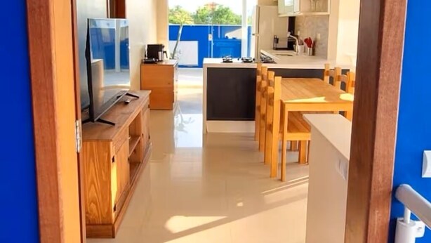 A modern kitchen with a dining area, wooden furniture, and a TV. - "Ap 06 Luz do Sol" 500m from Taperapuã Beach (Porto Seguro)