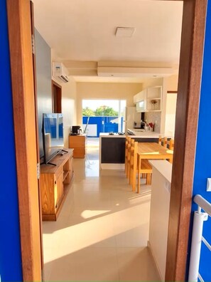 A modern kitchen with a dining area, wooden furniture, and a TV. - "Ap 06 Luz do Sol" 500m from Taperapuã Beach (Porto Seguro)