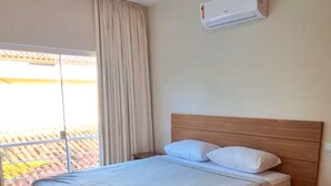 A bedroom with a bed, a window with curtains, and an air conditioning unit on the wall. - "Ap 06 Luz do Sol" 500m from Taperapuã Beach (Porto Seguro)