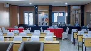 Een vergaderzaal met tafels, stoelen en een podium.