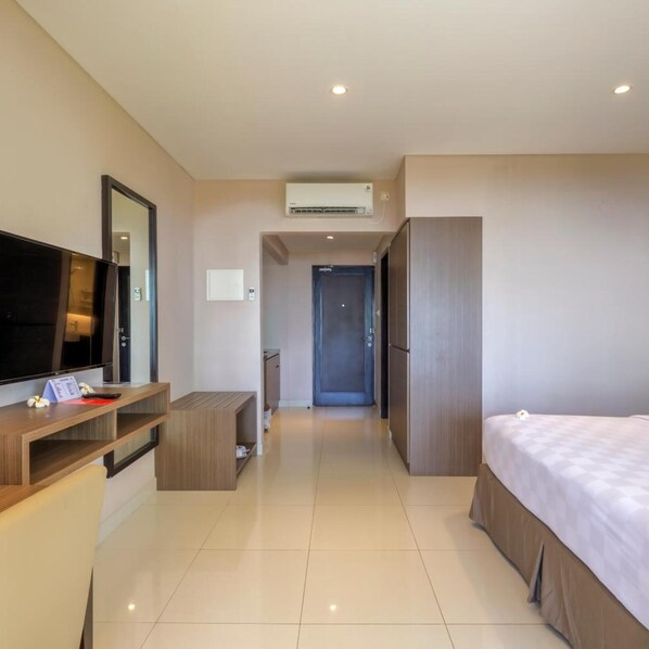 Une chambre d’hôtel équipée d’un lit, d’un bureau avec un ordinateur, d’une télévision, d’une armoire et d’un appareil de climatisation.