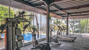 A gym with cardio machines, weightlifting equipment, and a view of a swimming pool. - Mambruk Anyer (Anyer)