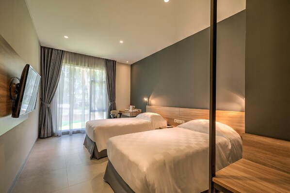 A hotel room with two beds, a desk, a chair, and a TV mounted on the wall.
