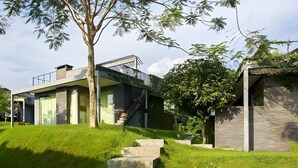 A modern house with a staircase leading to a wooden deck. - Tea Garden Resort (Sagalaherang)