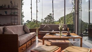 A modern living room with a sofa, a coffee table, and two poufs on a wooden floor. - Tea Garden Resort (Sagalaherang)