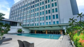 A modern hotel with a swimming pool, outdoor seating, and a large building facade. - Five Premiere Hotel (Samarinda)
