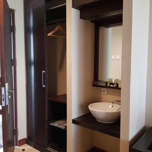 A bathroom with a white sink, a mirror, and a wooden hanger. - Jiwa Jawa Resort Bromo (Ngadisari)