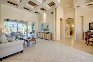 A spacious living room with a large sofa, a coffee table, and a dining area with chairs. - Heated Pool & Spa - Gulf Access Canal - 1 mile to Yacht Club Beach - BBQ (Cape Coral)