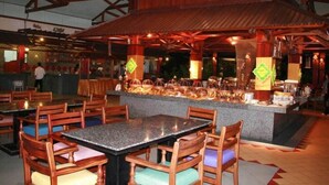 Un restaurante con mesas y sillas de madera, una barra con productos alimenticios y un techo alto con vigas de madera.