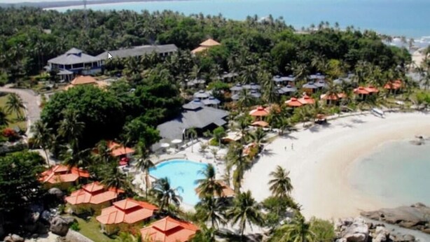 Un resort con piscina, playa y palmeras.