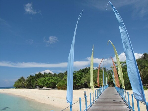 A wooden pier extending over a beach with a clear blue sky.