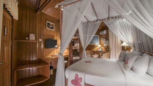Una habitación de madera con una cama con dosel, un televisor y un escritorio con una silla.