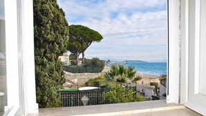 Un balcone con vista sulla spiaggia, un albero e una recinzione.