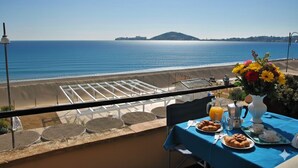 Un balcone con un tavolo apparecchiato per la colazione, con vista sulla spiaggia e sul mare.