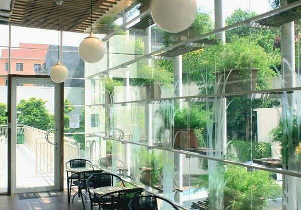 Een modern interieur met glazen wanden, een houten plafond en hangende, bolvormige lampen.