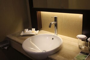 A bathroom with a white sink, a chrome faucet, and a tissue box on the counter.