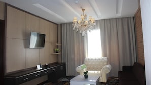 Una sala de estar moderna con una televisión de pantalla plana, una araña, un sofá y una mesa de centro.