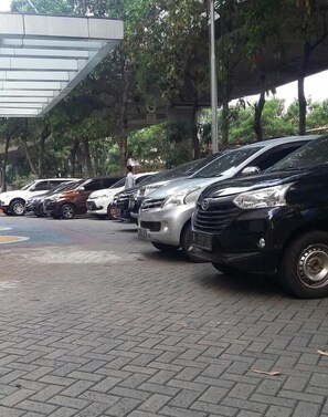 A parking area with several cars parked under a covered structure. - Sunbreeze Hotel Jakarta (Jakarta)