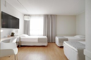 A hotel room with a bed, a desk, a chair, a TV, and a window with curtains. - Kauppahotelli Lahti (Lahti)