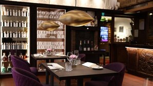A restaurant interior with tables set for dining, a bar area with bottles, and a wine display. - Woertz Schlosschen Zur Weinsteige (Stuttgart)