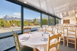 Ein Restaurant mit gedeckten Tischen, großen Fenstern mit Blick auf die Berge und einem modernen Interieur.