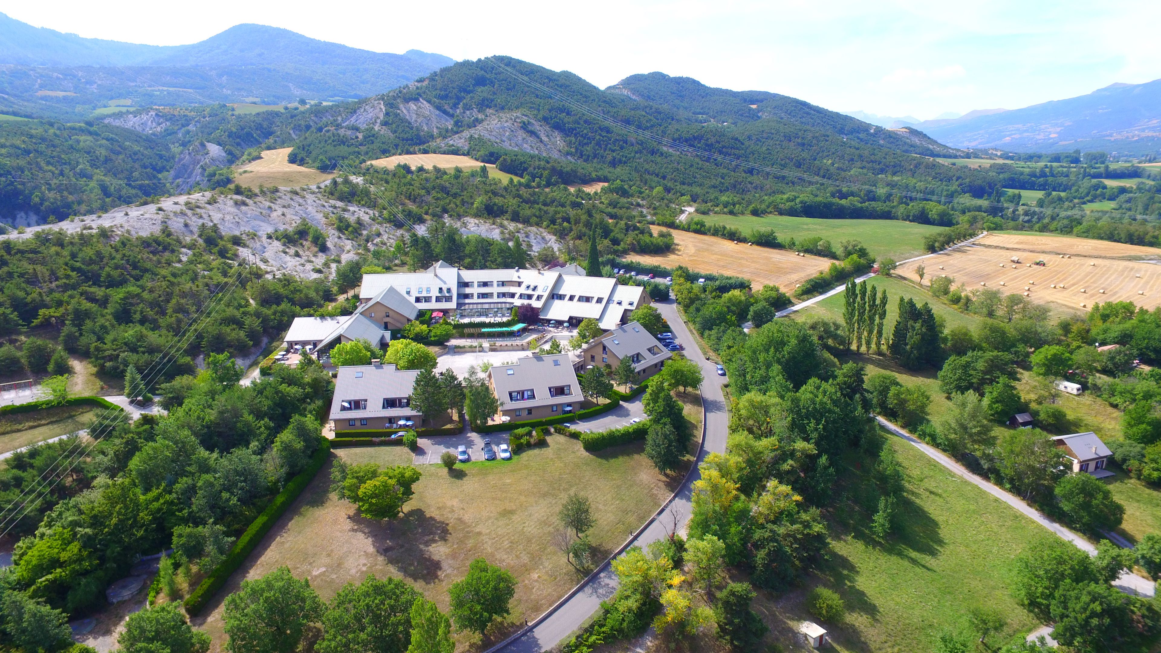 An aerial view of a modern building complex surrounded by lush greenery and mountains.