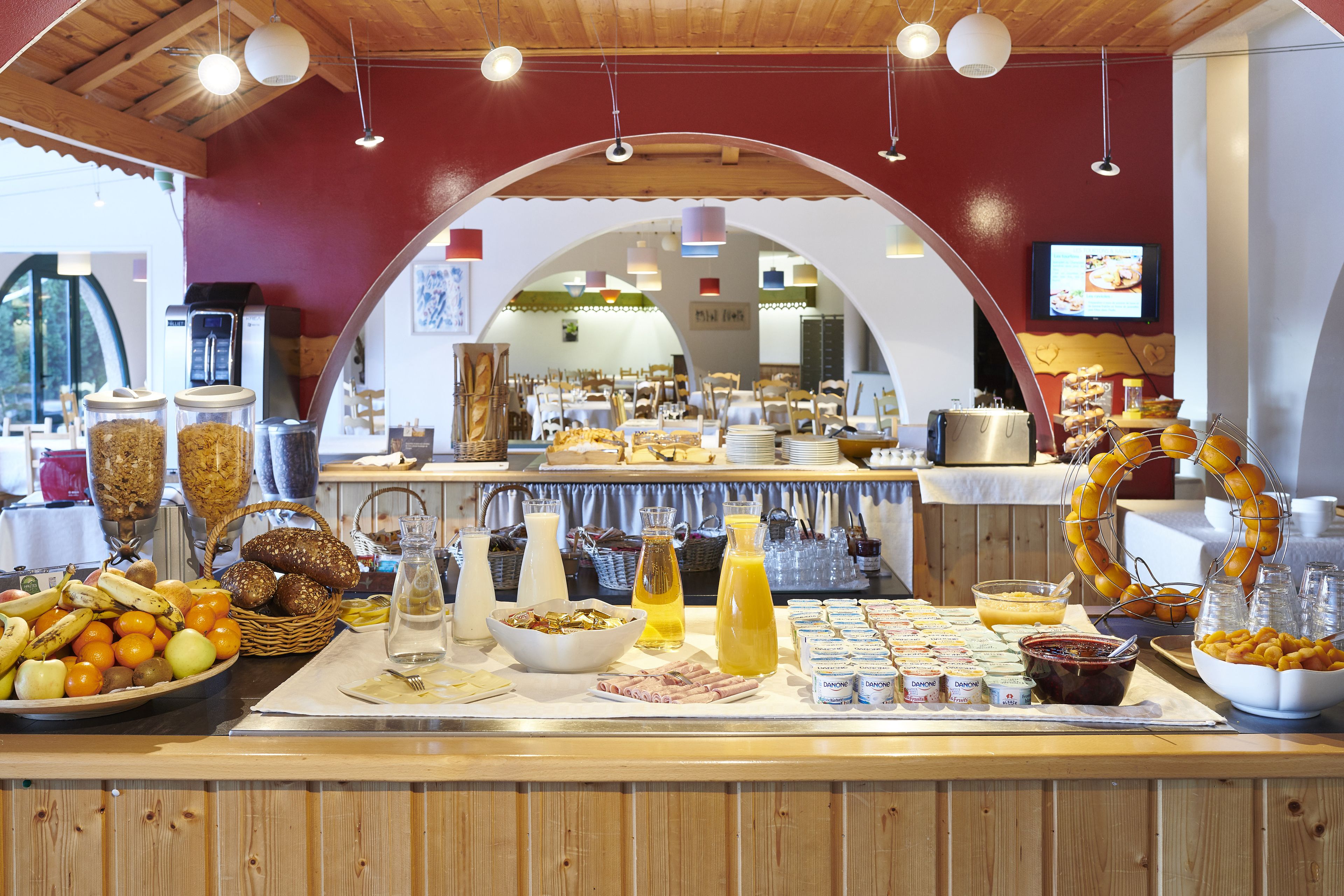 Un buffet proposant divers plats, une machine à café et un écran de télévision en arrière-plan.