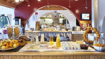 Un buffet proposant divers plats, une machine à café et un écran de télévision en arrière-plan.