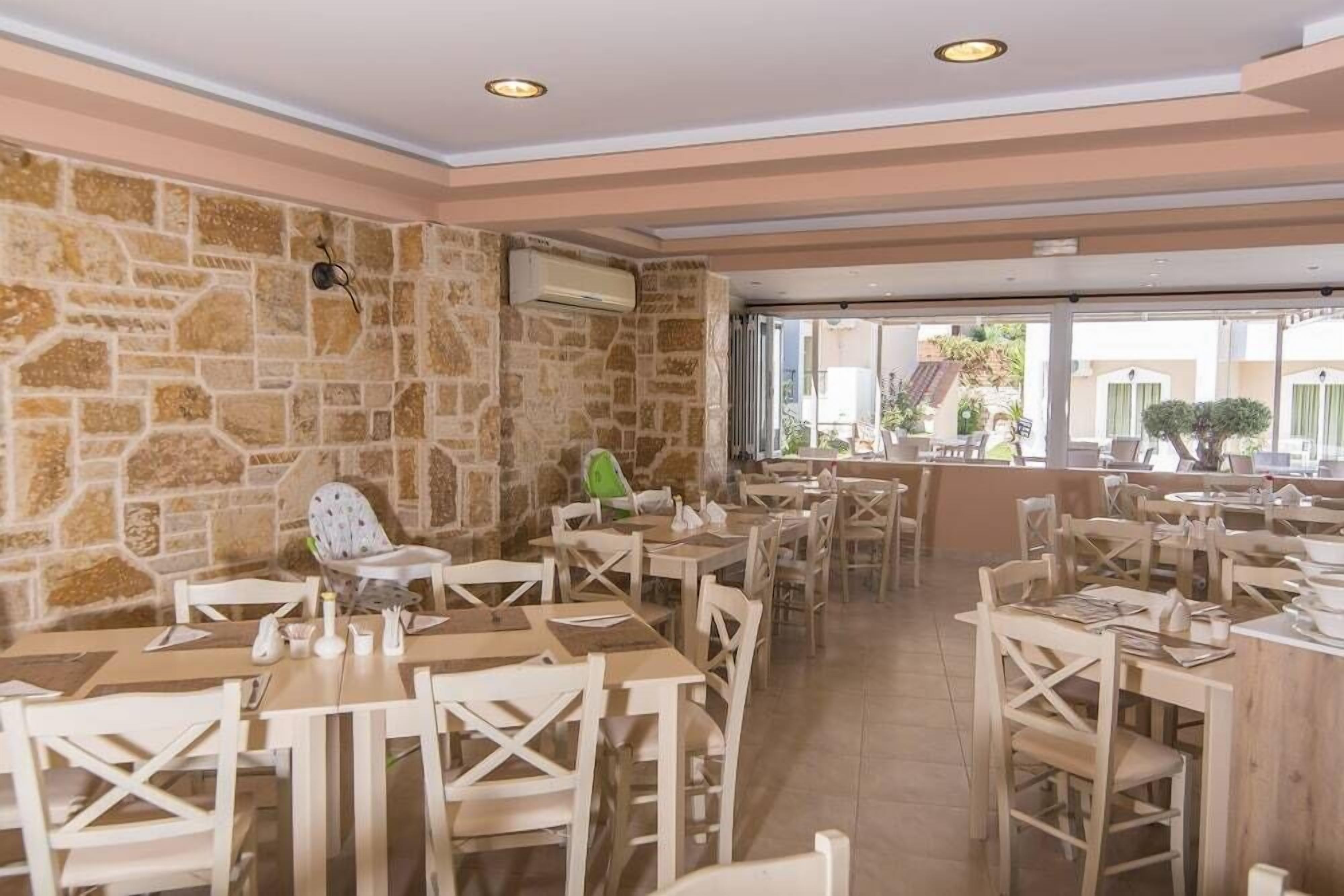 A restaurant with stone walls, wooden tables and chairs, and a view of the outside.