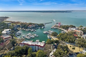 A marina with multiple boats docked, surrounded by residential buildings and a lighthouse. - Marsh View Sea Pines Villa, Steps to Harbour Town Marina, Dining & Shops (Hilton Head Island)