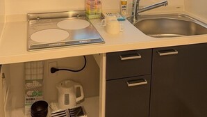 A compact kitchen with a window above the sink, a microwave, and a small cabinet below. - Minowa Station Hideaway - Breakfast + Free Coffee & Tea (台東区)