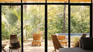 Ein Zimmer mit großen Fenstern, Holzmöbeln und Blick auf einen Garten.
