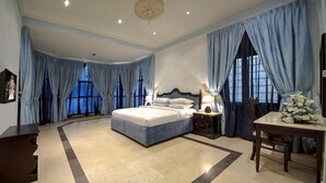 A spacious bedroom with a large bed, a nightstand, a table with flowers, and a chandelier. - Royal Residence Resort (Umm al Quwain)