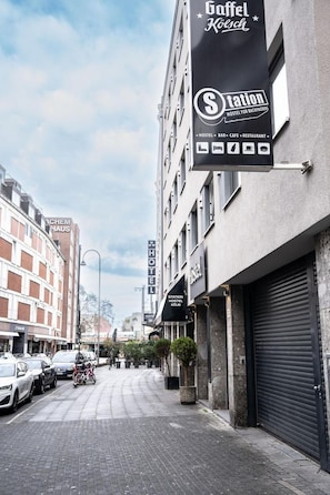 Une vue de rue avec un bâtiment sur lequel on peut voir une enseigne indiquant « Station Hostel Köln » et, au-dessus, une autre enseigne indiquant « Gaffel Kösch ».