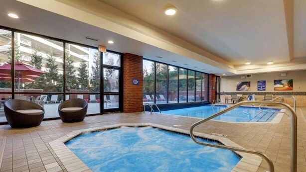 An indoor swimming pool with two separate sections, surrounded by large windows and wicker chairs. - Drury Plaza Hotel Columbus Downtown (Columbus)