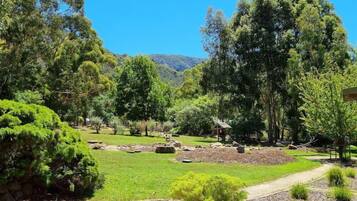 A landscaped garden with various trees, a small pond, and a pathway.