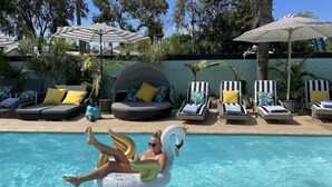 A pool area with lounge chairs, umbrellas, and a swan float. - Mulwala Murray River Motel (Mulwala)