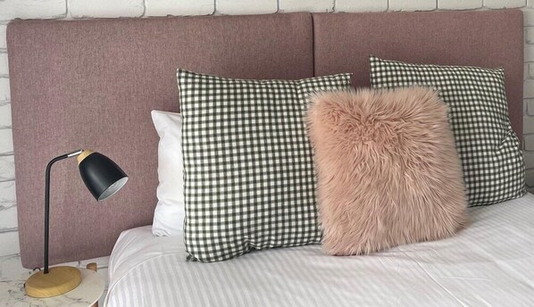 A bed with striped bedding, checkered pillows, a fluffy pillow, and a lamp on a marble floor. - Mulwala Murray River Motel (Mulwala)