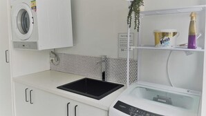 A compact laundry area with a washing machine, a sink, and a drying rack. - Mulwala Murray River Motel (Mulwala)