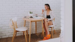 A person sitting at a round wooden table with a white chair, a small potted plant, and a framed picture on the wall. - Mulwala Murray River Motel (Mulwala)
