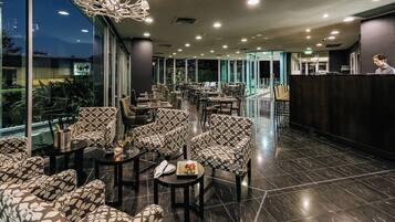 A spacious indoor area with multiple seating arrangements, including sofas and chairs, and a reception desk.