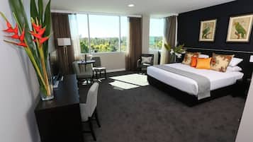 A hotel room with a large bed, a desk, a chair, and a view of the outdoors.