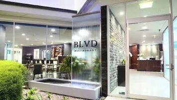 A BLVD restaurant with a reception area, indoor seating, and a small water feature outside.