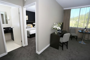 Une chambre d’hôtel comprenant un lit, un bureau, une chaise, une petite table et une vue sur l’extérieur.