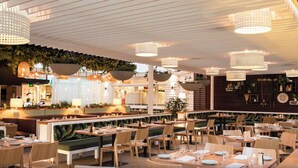 Un restaurant doté d’une grande salle à manger commune, de tables individuelles, de jardinières suspendues et de luminaires suspendus.