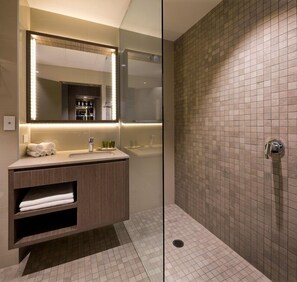 Une salle de bain moderne avec une douche à l’italienne en verre, un meuble-lavabo avec un miroir et un mur de douche carrelé.