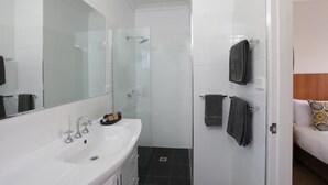 A modern bathroom with a white sink, a glass shower enclosure, and two towels hanging on a rack. - Cadman Motor Inn Tamworth (Tamworth)