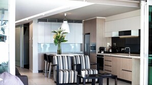 A modern kitchen with a dining area, featuring striped sofas, a coffee table, and a vase with flowers. - Seahaven Resort (Sunshine Coast)